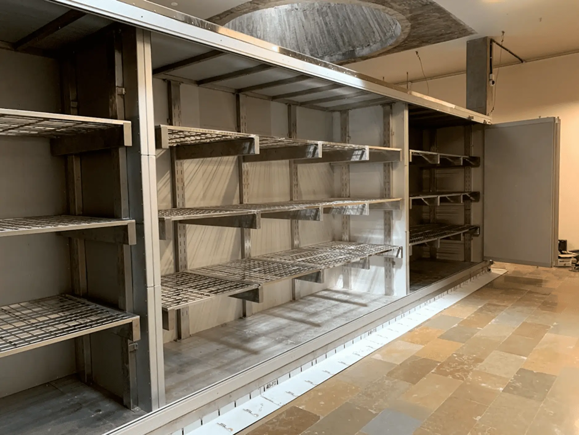 Custom fabricated mobile shelving system with metal grid shelves in an empty commercial storage space.